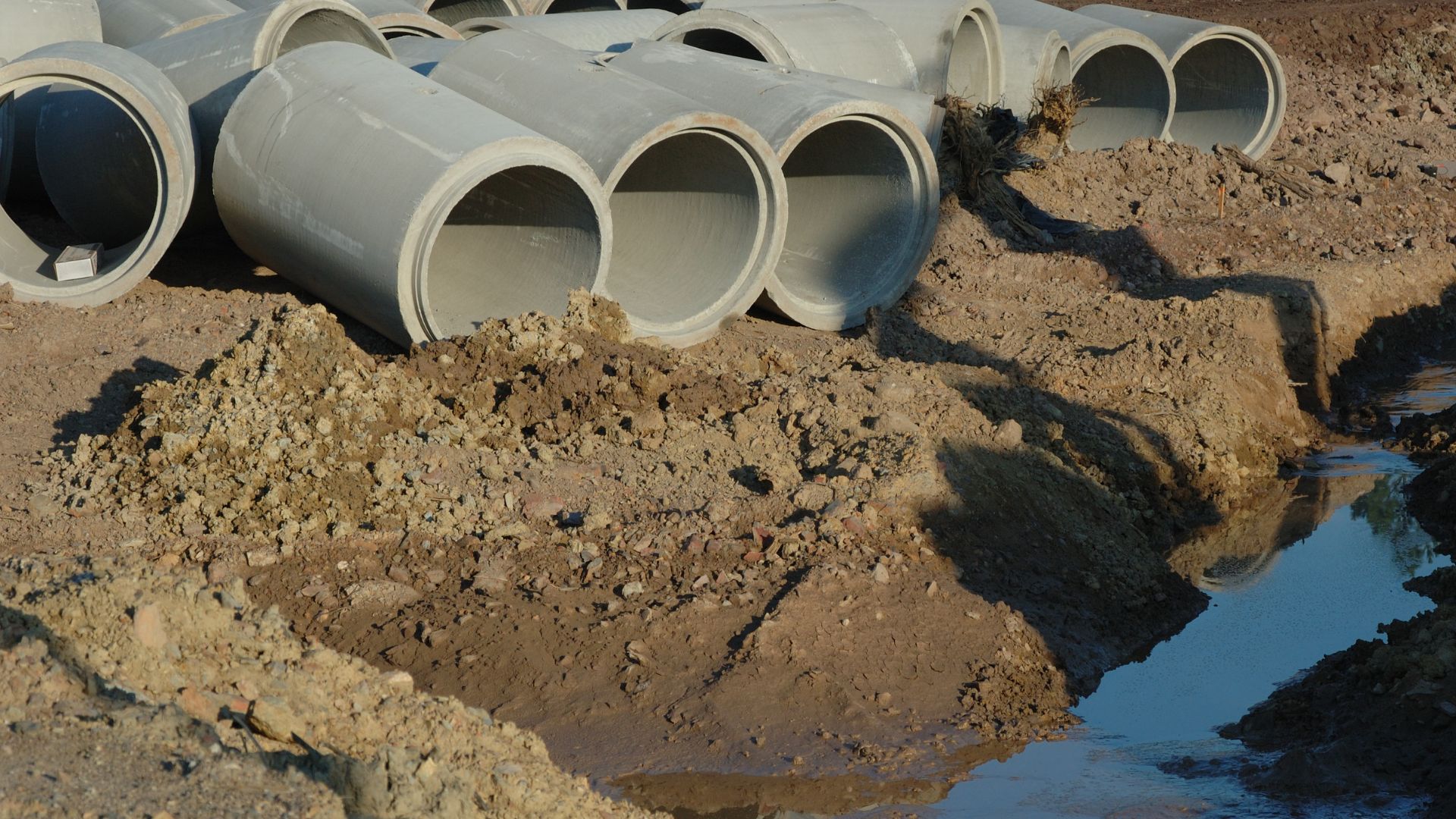 A pile of pipes sitting on top of a dirt field